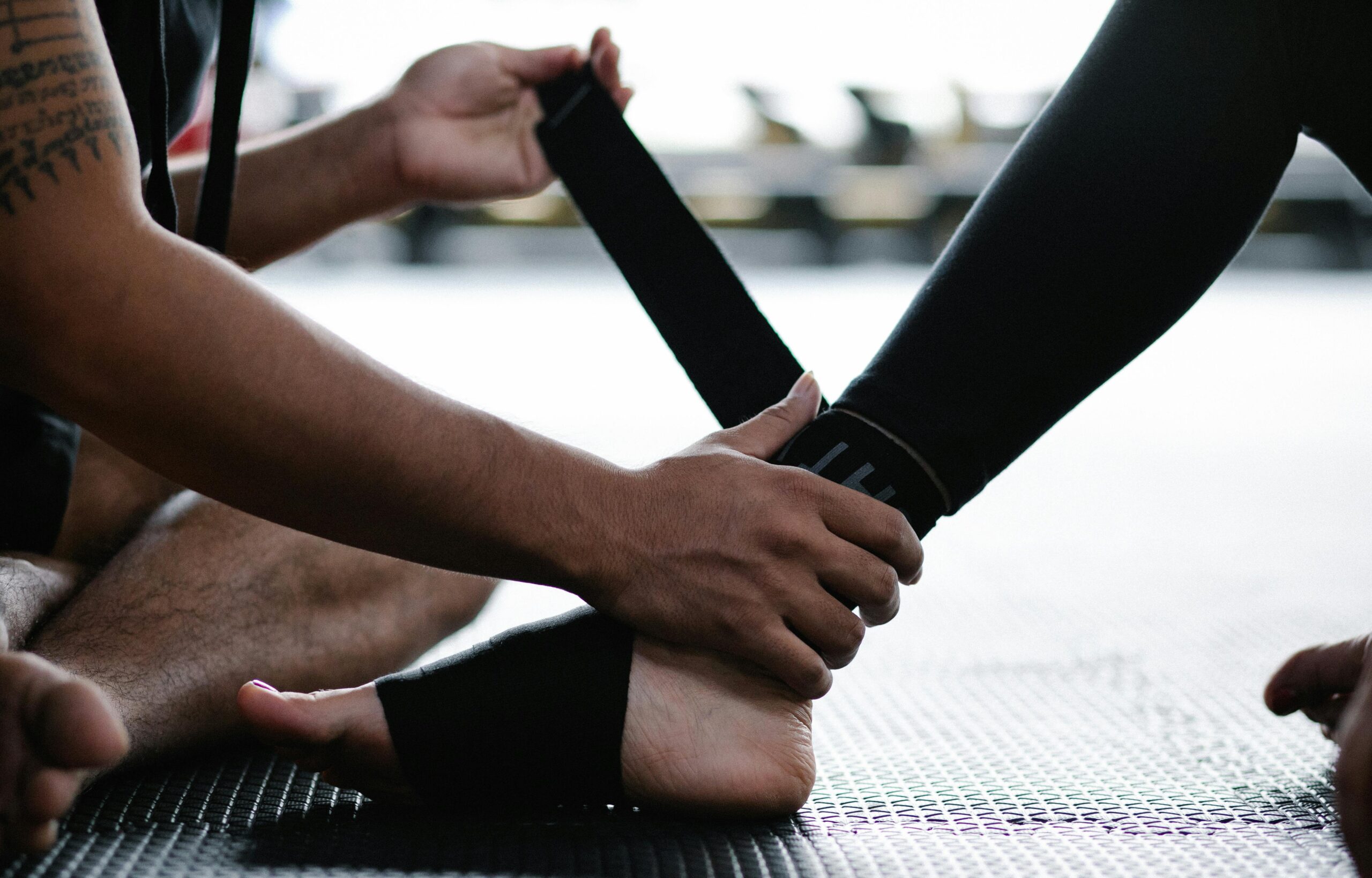 Close-up of an athlete's ankle being wrapped with an elastic bandage in a gym setting.