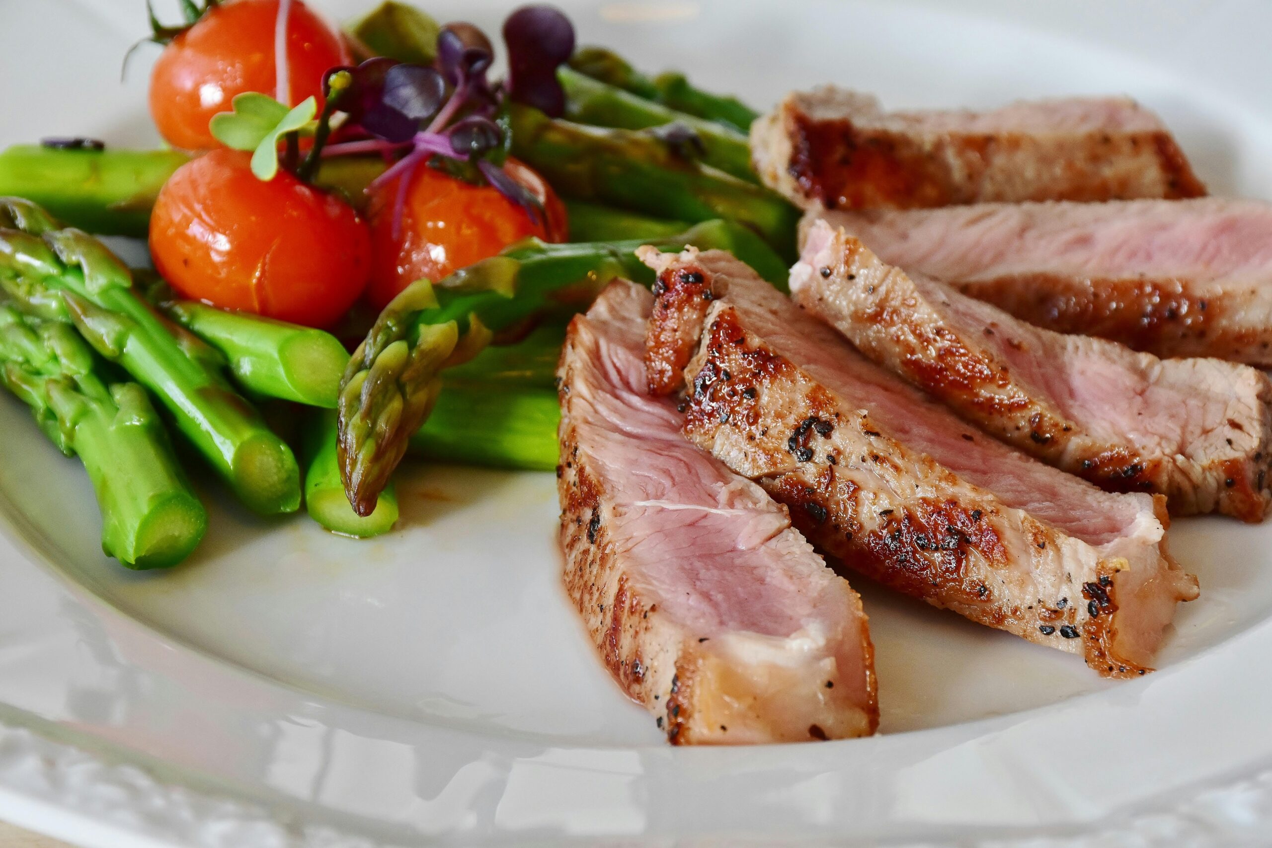 Close-up of grilled steak slices with asparagus and cherry tomatoes, perfect for a healthy meal.